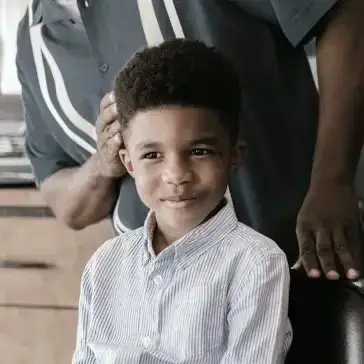 young boy sitting in barbers chair